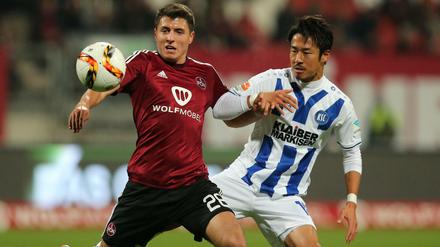 Nürnbergs Alessandro Schöpf (links) und der Karlsruher Hiroki Yamada haben den Ball im Blick.