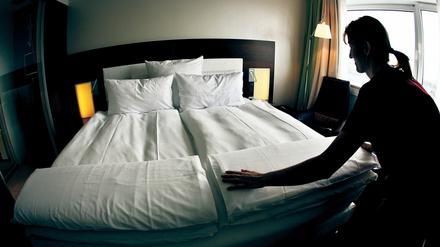 Ein Zimmermädchen macht in einem Hotel das Bett. 