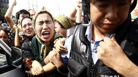Eine Angehörige der uigurischen Minderheit in China versucht einen Polizisten zu packen, während einer Demonstration in Ürümqi in der Unruheregion Xinjiang in Nordwestchina.