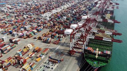 In einem Hafen der ostchinesischen Provinz Shandong wird ein Schiff mit Containern beladen. 