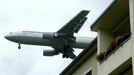 Eine Maschine Lufthansa fliegt über einem Haus im Berliner Stadtteil Reinickendorf zum Landeanflug auf den Flughafen Tegel.