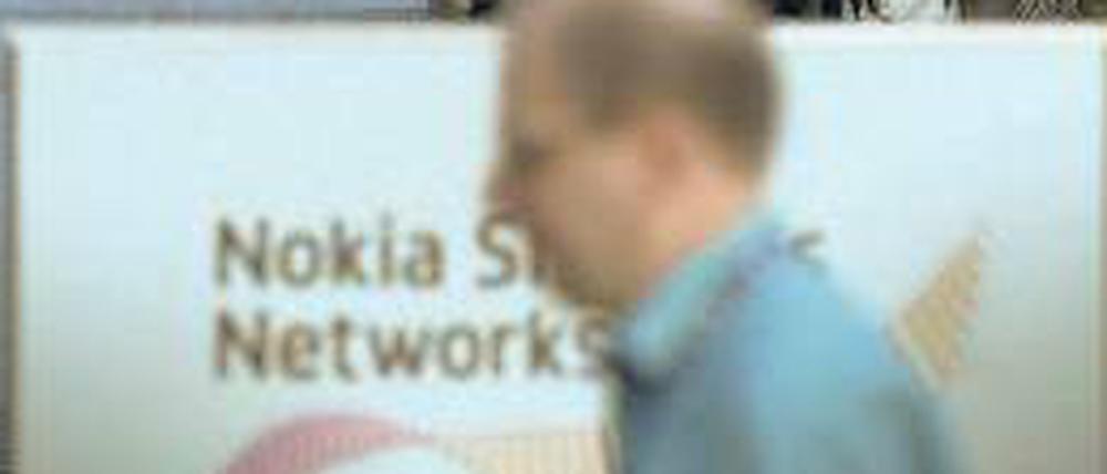 Ein Mann geht an einem Firmenschild von Nokia Siemens Networks in der Firmenzentrale in Espoo in Finnland vorbei. Nokia hält jetzt alle Anteile an dem Joint Venture