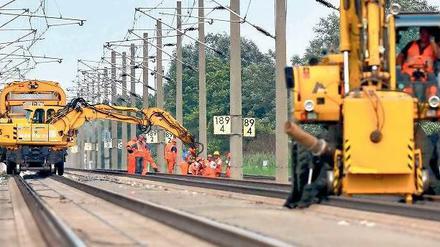 Bagger und Arbeiter in orangefarbenen Schutzanzügen stehen auf den Schienen der gesperrten Bahntrasse