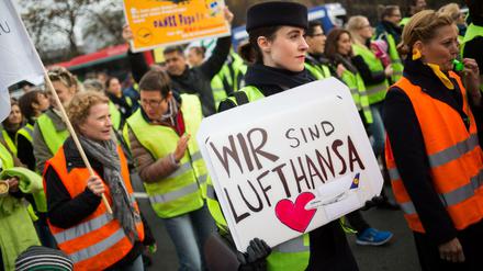 Eine Lufthansa-Mitarbeiterin hält in Frankfurt am Main bei einer Kundgebung vor Konzernzentrale der Fluggesellschaft am Flughafen ein Plakat mit der Aufschrift "Wir sind Lufthansa". 