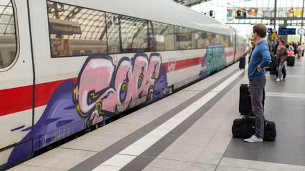 Kunst oder Vandalismus? Ein Passagier steht am Berliner Hauptbahnhof vor einem mit Graffiti beschmierten ICE.