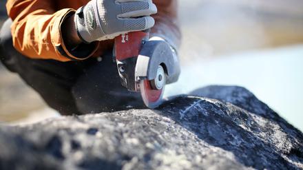 Eine Person bearbeitet Felsgestein mit einer Flex.