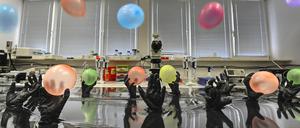 Die polnische Akademie der Wissenschaften zeigt mit diesem Bild das Konzept der Klick-Chemie: Nanopartikel aus Gold, hier die Ballons, werden von Stickstoffschnallen, hier als Hände dargestellt, an eine Kohlenstoffoberfläche, hier Wasser, gebunden.