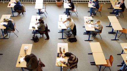 Schülerinnen und Schüler sitzen bei einer Abiturprüfung an Einzeltischen.