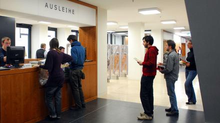 Studierende stehen in einer Bibliothek der Humboldt-Uni an der Buchausleihe.