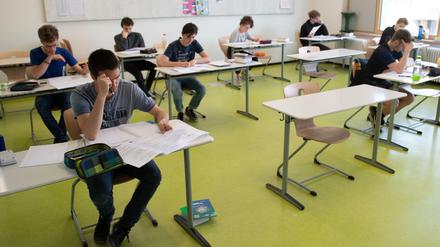 Schüler sitzen beim schriftlichen Abitur an Einzeltischen, einige Tische sind freigeblieben.