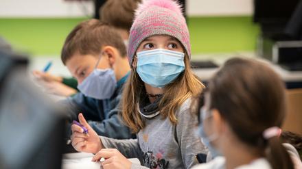 Ein Mädchen trägt im Unterricht Maske und hat eine Mütze auf.