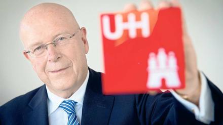 Dieter Lenzen, Präsident der Uni Hamburg, hält das Universitätslogo in die Kamera.