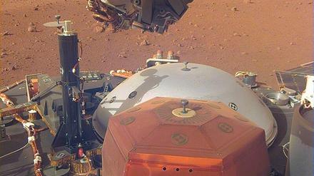 Am 26. November 2018 setzte die Nasa-Sonde „Insight“ in Äquatornähe des Roten Planeten auf. An Bord war ein Seismometer (rot), das mit einem Roboterarm neben dem Lander abgesetzt wurde und mit einer Haube vor Wind und Staub geschützt wird (weißgrau hinter dem roten Seismometer). Auch der „Maulwurf“ Berliner Forscher wurde von seinem Platz auf dem Lander (der schwarze, schmale Aufbau neben dem Schutzschild) auf den Marsboden versetzt. 