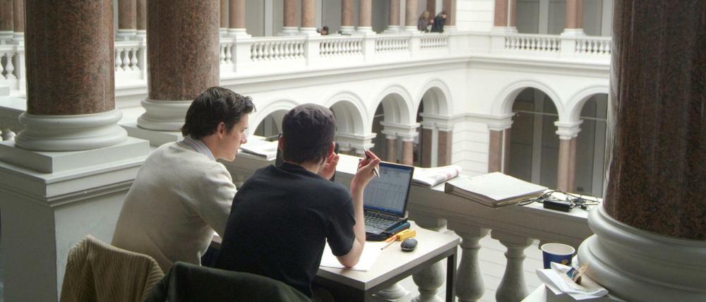 Zwei Studenten lernen an einem Tisch im Lichthof der Technischen Universität Berlin.